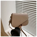 Detail der beigen Satteltasche mit gewölbter Klappe und geprägtem Fashion Trend Text - Khaki