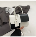 Detalle de un bolso elegante bicolor blanco y negro con acabado pulido y etiqueta - Negro