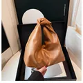 Detail einer braunen Handtasche aus Leder mit geknotetem Griff und modischem Plissee-Design - Khaki