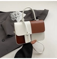 Detalle de costuras en contraste bicolor en un bolso de cuero premium con una etiqueta - Marrón Rojo