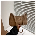 Close-up of a woven texture shoulder bag with a gold bow accent and zipper detail - Tan