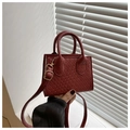 Detail van wijnrode mini-tas met geweven textuur en goudkleurige metalen accenten - Rood