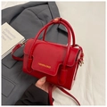 Detailaufnahme der roten Lackleder-Handtasche mit goldenen Beschlägen und Schriftzug - Rot