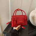 Minimalistische rote Ölwachsleder Handtasche auf Dekobuch mit modischen Goldbuchstaben - Rot