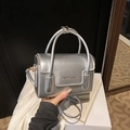 Petit sac carré argenté avec fini métallique et bandoulière amovible tenu à la main - Argent