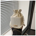 Close-up of white bucket bag with pearl handle and snake-embossed leather texture - White