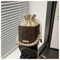 Detail of snake pattern leather texture and pearl handle on a brown bucket bag - Coffee