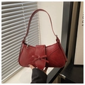 Detail view of red underarm bag with vintage leather texture and elegant bow design - Red