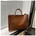 Dettaglio borsa tote marrone effetto coccodrillo con manici curvi su un davanzale della finestra - Marrone