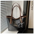 Dettaglio della grande borsa tote con texture nera e manici marroni a contrasto - Nero