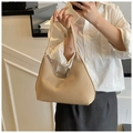 Minimalistische Hobo-Tasche aus Strohgeflecht, getragen von einem Model im modernen Stil - Khaki