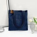 Large dark blue denim tote bag with leather patch on a clean minimalist background - Stitched Outer Pocket Style