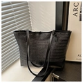 Detail of black woven tote bag showing herringbone texture and smooth leather base - Black