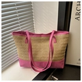 Close-up of woven straw tote bag featuring bright pink leather trim and dual long handles - Pink