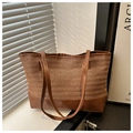 Detail of woven straw and leather tote bag featuring elegant light and shadow play - Brown