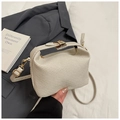 Detail der cremefarbenen Webhandtasche mit Goldbeschlägen und plissierter Struktur - Weiß