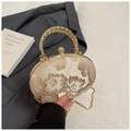 Detail of floral embroidery, woven metal handle, and pearl clasp on a gold evening clutch - White