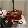 Detalle de un bolso caja de cuero rojo oscuro brillante con doble cremallera plateada - Rojo