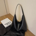 Grande borsa a spalla hobo minimalista in ecopelle nera su una superficie in legno - Nero