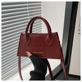 Detalle de bolso burdeos con grabado de cocodrilo y letras doradas de moda - Rojo