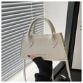 Detalle de bolso blanco con textura de cocodrilo, letras doradas y asa de mano - Blanco