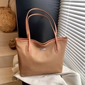 Braune gewebte Shopper-Tasche mit silbernem Logo-Schild auf weißem Blazer mit Schatten - Braun