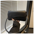Close-up of matte black underarm bag with unique wave-edge flap and premium leather texture - Black