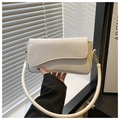 Close-up of cream underarm bag featuring wave edge flap and gold hardware detail - White