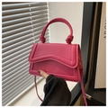 Detalle de mini bolso rosa fucsia con costuras onduladas y asa superior con nudo - rosa intenso