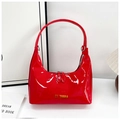 Detalle de bolso de charol rojo con letras doradas y cierre de cremallera doble - Rojo