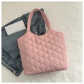 Detailed view of pink quilted tote bag with wavy stitching on white texture background - Light Pink