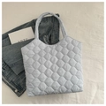 Gros plan du sac cabas matelassé bleu clair sur une surface blanche avec accessoires - Bleu