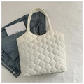 Gros plan du sac cabas matelassé blanc sur tissu avec livre d'art et décor de denim - Blanc