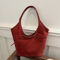 Retro burgundy frosted leather tote bag with bow detail in a minimalist scene - Red