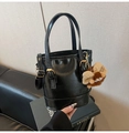 Detailansicht der schwarzen Lackleder-Beuteltasche mit Plüschanhänger und Gold-Hardware - Schwarz (Mit Anhänger)