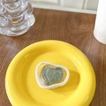 Close-up of a heart-shaped phone grip with green stone texture on a yellow tray - Green