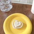 Detail of a white heart-shaped phone grip on a yellow ceramic plate with wooden background - Marbled Apricot White