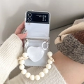Detail of Galaxy Z Flip 6 clear case with white heart charm and cream pearl wrist strap - White / Samsung ZFlip3