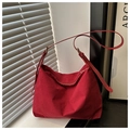 Detail einer burgunderroten Wildledertasche mit verstellbarem Riemen und matter Oberfläche - Rot