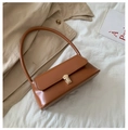 Close-up of caramel leather baguette bag with gold square buckle on fabric background - Tan