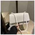Detalle de bolso baguette blanco con textura trenzada y herrajes metálicos dorados - Blanco