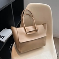 Minimalist beige oversized tote bag in smooth leather on an elegant white designer chair - Khaki