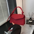 Red woven crossbody bag with knotted handle and shoulder strap shown in a modern home setting - Red