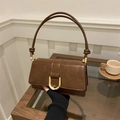 Dettaglio borsa in pelle testa di moro con grande fibbia dorata a U e nodi decorativi - Marrone