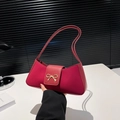 Bolso baguette de cuero rojo oscuro con hebilla de lazo dorado en una mesa blanca - Rojo