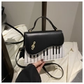Detailed shot of the piano keyboard pattern and gold treble clef metal charm on the bag - Black
