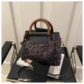 Detail of leopard print handbag with wooden handle and gold rivets on a chair - Black