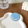 Close-up of a light blue magnetic collapsible phone grip on a white cloud tray - Blue