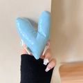 Detail of light blue padded heart phone grip with glossy leather texture and woven label - Warped Heart (Blue)