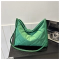 Detalle de un bolso tote verde acolchado sobre una mesa con elementos de estilo - Verde
